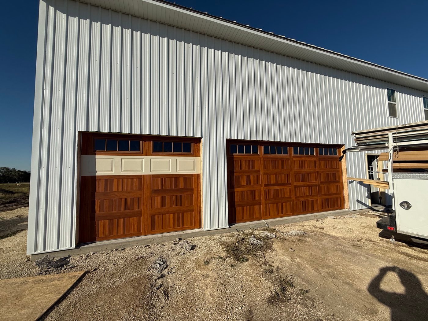 Two cedar-look carriage doors on a white steel building