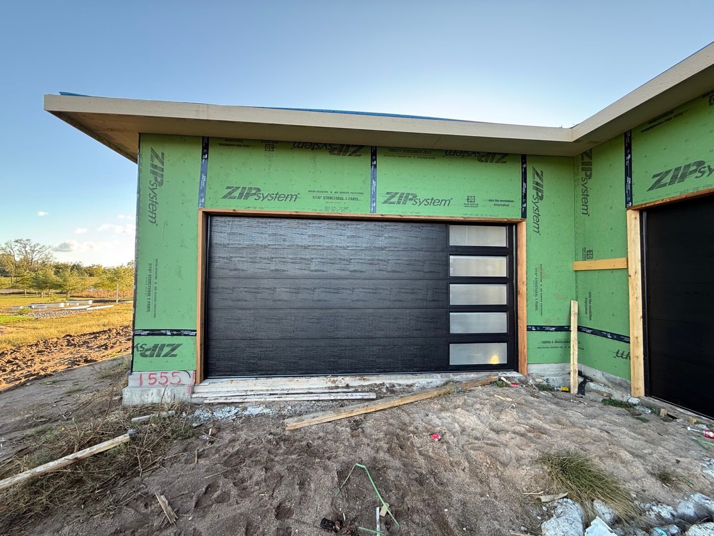 Black flush garage door with vertical glass on new construction