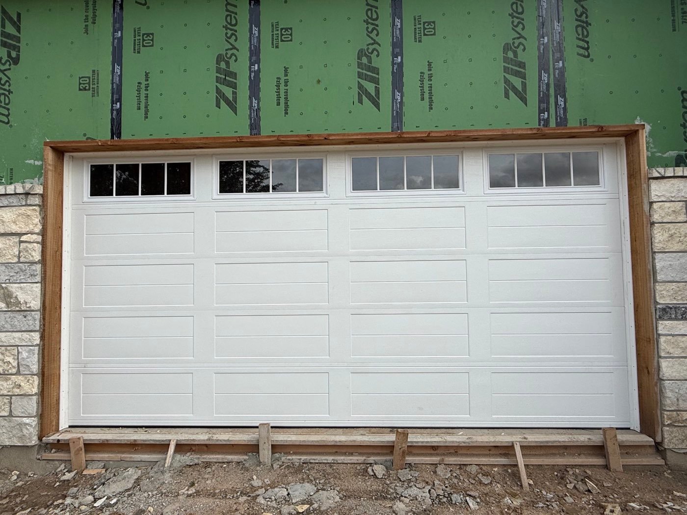 White raised-panel garage door with windows on a new build